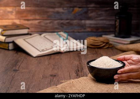 Saint Coran et un grain de riz dans un bol en bois dans le sac sur une table en bois, concept de zakat islamique. Musulmans pour aider les pauvres et les nécessiteux. Conceptuel s Banque D'Images