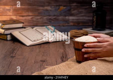 Saint Coran et un grain de riz dans un bol en bois dans le sac sur une table en bois, concept de zakat islamique. Musulmans pour aider les pauvres et les nécessiteux. Conceptuel s Banque D'Images