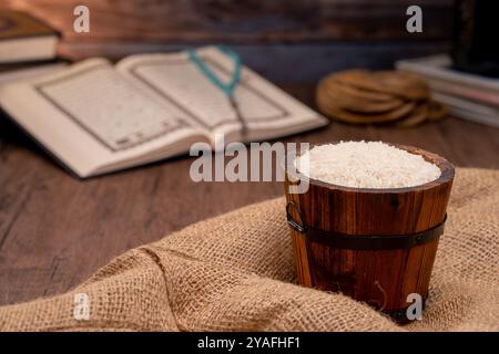 Saint Coran et un grain de riz dans un bol en bois dans le sac sur une table en bois, concept de zakat islamique. Musulmans pour aider les pauvres et les nécessiteux. Conceptuel s Banque D'Images