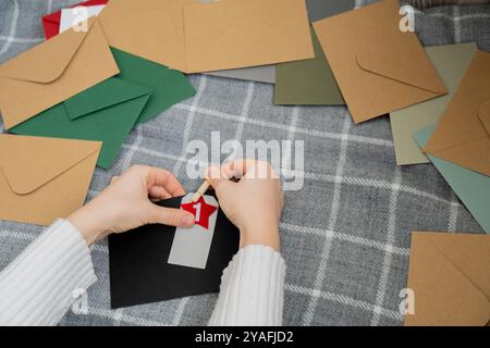 Numéro sur les enveloppes d'artisanat notes avec des tâches avant les vacances de Noël. Femme faisant du papier kraft pour calendrier de l'Avent fait à la main fait de vos propres mains étape par étape bricolage artisanat faites-le vous-même Banque D'Images