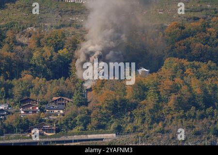 Village dans la forêt automnale avec la fumée montante, entouré de montagnes, lac de Brienz, Suisse, Europe Banque D'Images