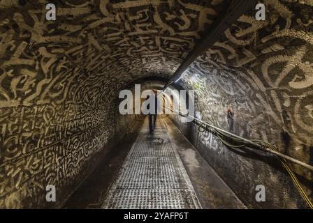 Anderlecht, Bruxelles, Belgique, 07 16 2019- homme marchant dans les intérieurs industriels du musée des égouts montrant le tunnel principal de la chaussée de Mons Banque D'Images