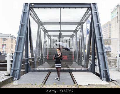 Bruxelles, Belgique, 03 13 2018 : Portrait d'une fillette de vingt ans avec un parapluie et une vieille locomotive à l'arrière-plan, Europe Banque D'Images