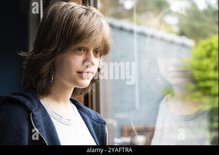 Portrait d'une jeune fille de 15 ans rêveuse regardant par la fenêtre, Herentals, Belgique, Europe Banque D'Images