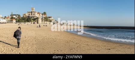 Estoril, Portugal, 12 29 2018 : très grande vue panoramique d'une jeune femme marchant sur la plage par un après-midi d'hiver ensoleillé, Europe Banque D'Images