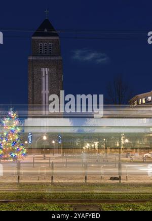 Jette, région de Bruxelles-capitale, Belgique, 12 20 2020, sentiers lumineux d'un tramway à l'avenue Charles Woeste pendant l'heure bleue avec la tour de l'église Banque D'Images