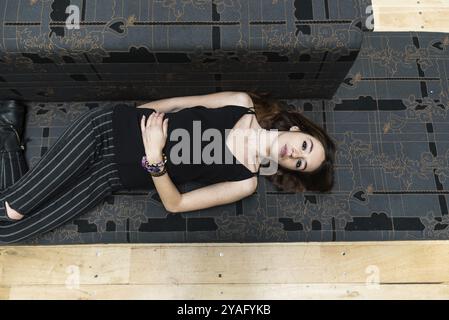 Portrait de mode d'une jolie fille de 18 ans aux cheveux rouges couchée sur un canapé Banque D'Images
