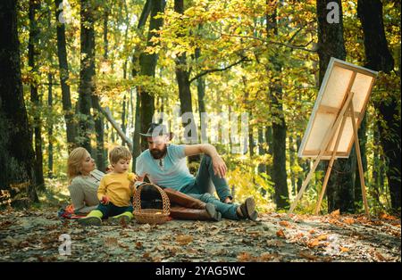 Dessiner de la vie. Artiste peintre avec famille se relaxant dans la forêt. Peinture dans la nature. Démarrer une nouvelle photo. Capturez l'instant. Beauté de la nature. Femme Banque D'Images