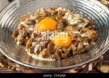 Oeufs avec de la viande rôtie dans une poêle en cuivre sur une table en bois. Nom turc kavurmali yumurta Banque D'Images