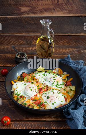 Shakshuka dans une poêle. Oeufs frits avec tomate, poivre, courgettes et herbes Banque D'Images