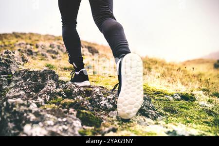 Gros plan sur les jambes du coureur, les pieds avec des chaussures de course durig jogging hors route dans la nature sur sentier de course en terre battue. Banque D'Images