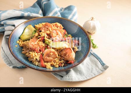 Crevettes ou crevettes avec du riz et des légumes sur une assiette bleue et un torchon de cuisine sur un fond en bois clair, cuisine saine à la maison, foyer sélectionné, Banque D'Images