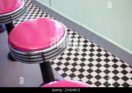 Tabourets magenta au sol à carreaux dans un restaurant rétro Banque D'Images