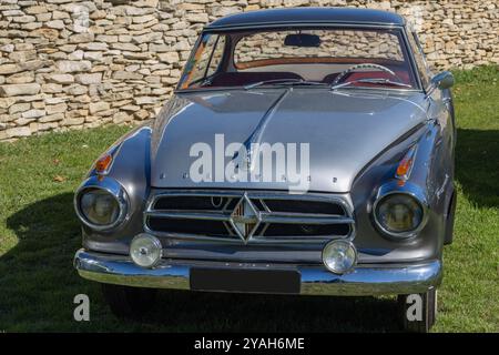 Coupé borgward isabella argenté et noir garé sur l'herbe devant un mur de pierre Banque D'Images