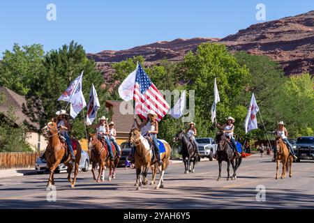 Une équipe d'exercices équestres à cheval avec un drapeau américain lors de la parade du 4 juillet le jour de l'indépendance à Moab, Utah. Banque D'Images