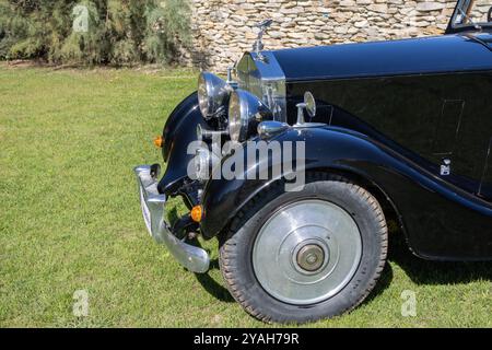 Rolls vintage noir brillant royce garé sur l'herbe montrant son emblématique ornement de capot, son aile et sa roue avant Banque D'Images