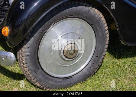 Gros plan d'un pneu et d'un enjoliveur sur une Rolls royce vintage, montrant le détail de la bande de roulement du pneu et le logo Rolls royce Banque D'Images