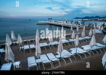 Plage de sable incroyable à Cannes le matin (pas de gens) : auvents de soleil blanc plié et chaises de bain de soleil attendant les gens pour bonne journée d'été sur le R français Banque D'Images