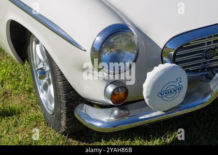 Gros plan d'une voiture classique volvo p1800 blanche montrant la calandre chromée, le phare et le pare-chocs Banque D'Images