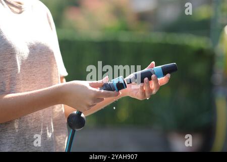 Gros plan d'une main de femme assemblant la buse de tuyau dans un jardin Banque D'Images