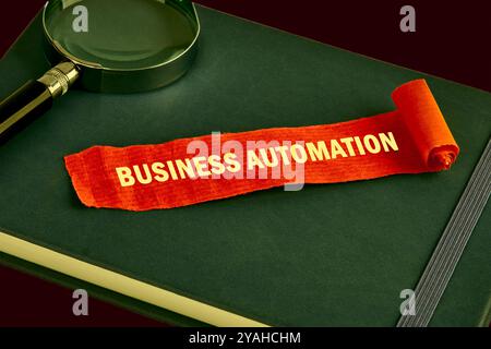 Le concept du business de l'information. Le texte de l'AUTOMATISATION DES AFFAIRES est écrit sur un morceau de note rouge déplié, papier sur un livre vert. Couleurs saturées. Banque D'Images