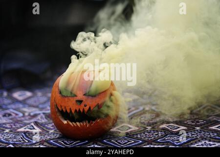 Citrouille sculptée Jack-o-lanterne avec bombe fumée de couleur Banque D'Images