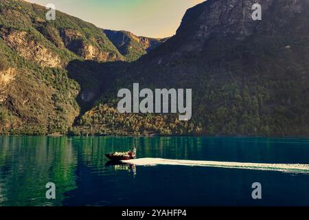 7 septembre, 2024 Flam, Norvège Un bateau de tourisme ÒspeedyÓ Fjord Safari écume l'Aurlandsfjord dans la lumière tôt le matin - vu de l'ele Banque D'Images