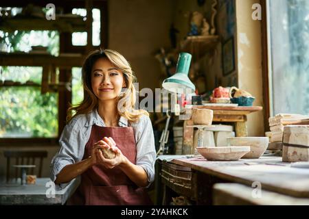 Potier féminin sculpte dans l'argile dans son atelier. gros plan sur le processus de façonnage de l'argile brute. Maîtriser l'art de la céramique artisanale de poterie Banque D'Images