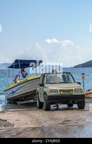 Bateau lancé sur une cale publique à l'aide d'une petite jeep Suzuki pour abaisser progressivement l'engin sur la pente dans la mer Banque D'Images