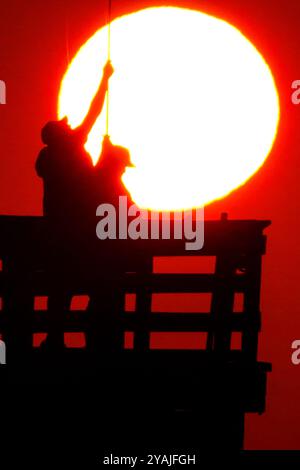 Île de Palms, États-Unis. 14 octobre 2024. Pêcheur silhouetté par un lever de soleil spectaculaire jeta leurs lignes au large de l'embarcadère de l'île de Palms, le 14 octobre 2024 à l'île de Palms, Caroline du Sud. Ciel dégagé et temps chaud sont dans les prévisions pour le lowcountry. Crédit : Richard Ellis/Richard Ellis/Alamy Live News Banque D'Images