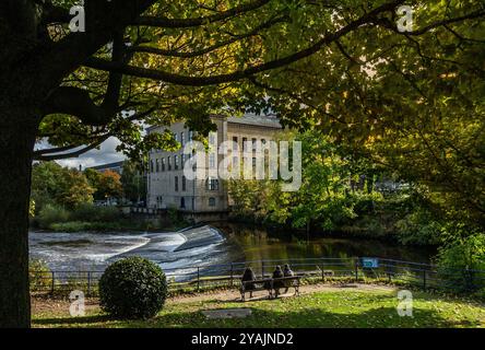 Regardant à travers le moulin à sels, Saltaire de Roberts Park à Baildon en automne. La rivière aire coule sur un déversoir entre le moulin et le parc. Banque D'Images