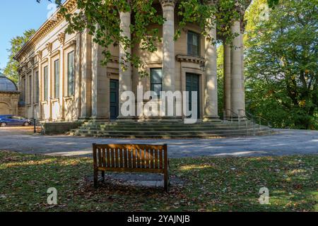 Un siège en bois dans le parc de l'église réformée unie Saltaire, Yorkshire. Ce bâtiment classé Grade 1 se trouve dans le village victorien modèle de Saltaire. Banque D'Images