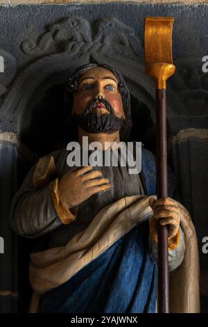 Saint Jacques, fils d’Alphée, l’un des 12 Apôtres de Jésus. Tête et corps supérieur d’une des 12 statues d’apôtres polychromes, sculptées en bois en 1721, qui flanquent l’entrée d’une église bretonne, L’Eglise Saint Sauveur au Faou, Finistère, Bretagne, France. Banque D'Images