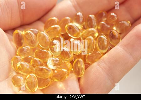 Capsules dorées d'huile de poisson oméga-3 en main pour des suppléments de santé et de bien-être. Banque D'Images