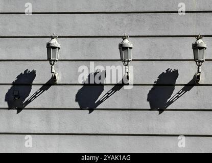 Trois lanternes de style ancien : rythme et motif de lumière et d'ombre sur le mur extérieur Banque D'Images