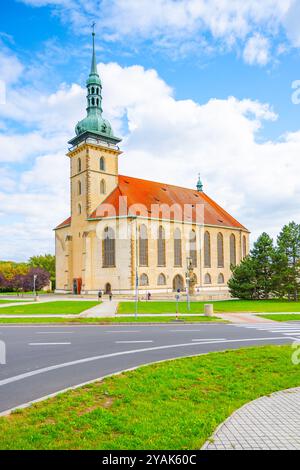 L'église de l'Assomption de la Vierge Marie présente dans la plupart des cas sa superbe architecture gothique tardive sous un ciel partiellement nuageux. Les visiteurs se promènent dans les environs verdoyants. Banque D'Images