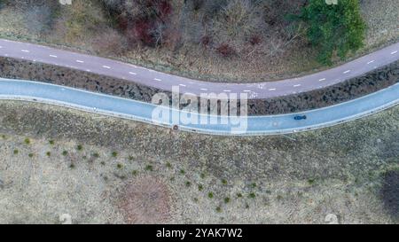 Vue aérienne d'une route piétonne sinueuse et cyclable à travers une zone boisée avec une végétation clairsemée. Banque D'Images