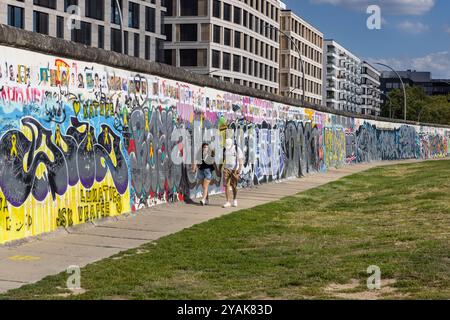 Les gens marchent le long de l'arrière de la East Side Gallery, partie du mur de Berlin à Friedrichshain, Berlin, Allemagne Banque D'Images