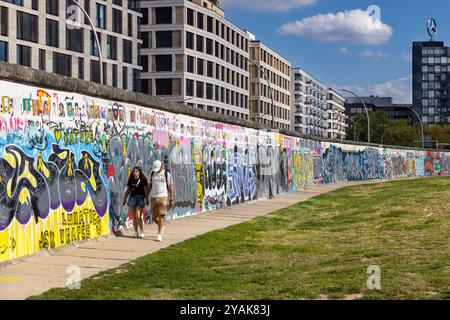 Les gens marchent le long de l'arrière de la East Side Gallery, partie du mur de Berlin à Friedrichshain, Berlin, Allemagne Banque D'Images