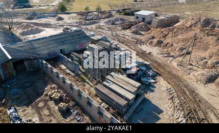 Vue aérienne d'un empilement de vieilles dalles de béton site de stockage, piles de terre, et quelques petits bâtiments. La zone est entourée d'une clôture, et il y a vi Banque D'Images