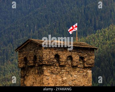 le drapeau de la géorgie flotte au sommet de l'une des tours défensives médiévales de mestia georgia Banque D'Images