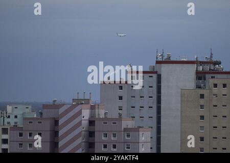 Francfort, Hesse, Allemagne. 14 octobre 2024. Un avion survole des immeubles résidentiels par temps froid à Francfort, en Allemagne. Crédit : ZUMA Press, Inc/Alamy Live News Banque D'Images