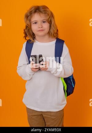 Écolier envoyant un message texto à l'aide de smarpthone sur fond jaune isolé Banque D'Images