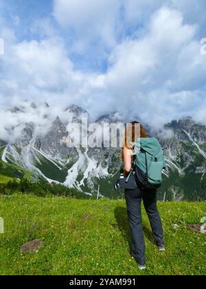 Une jeune fille se tient au premier plan, admirant la vue imprenable sur les Alpes autrichiennes Banque D'Images