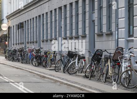 Rangées de vélos garées le long d'une façade de maison de ville grise, Copenhague, Danemark, Europe Banque D'Images