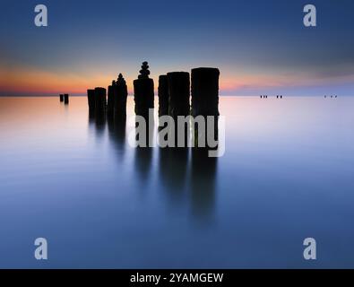 Pyramides de pierre sur les vieux groynes avec des algues dans l'eau sur la plage de la mer Baltique, longue exposition au coucher du soleil, Wustrow, Fischland-Darss-Zingst peninsu Banque D'Images