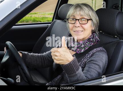 Les personnes âgées en voiture abandonnent les pouces Banque D'Images