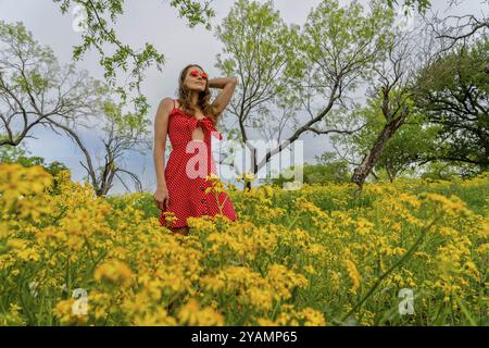 Un beau modèle brune profite d'un champ de fleurs jaunes un jour de printemps Banque D'Images