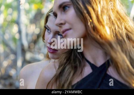 Double allure : deux superbes mannequins prennent des poses dans les champs de mangrove du centre du Mexique, baignés par le coucher du soleil du Yucatan lors d'une escapade fascinante Banque D'Images