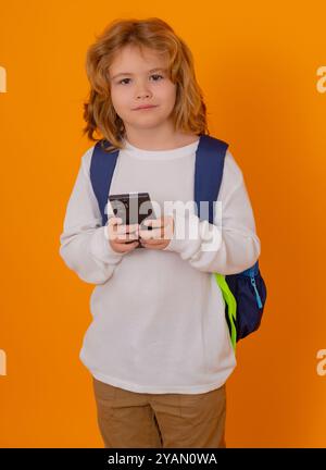 Écolier envoyant un message texto à l'aide de smarpthone sur fond jaune isolé. Banque D'Images